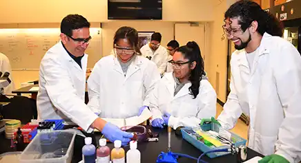 Professor interacting with a group of students in a lab