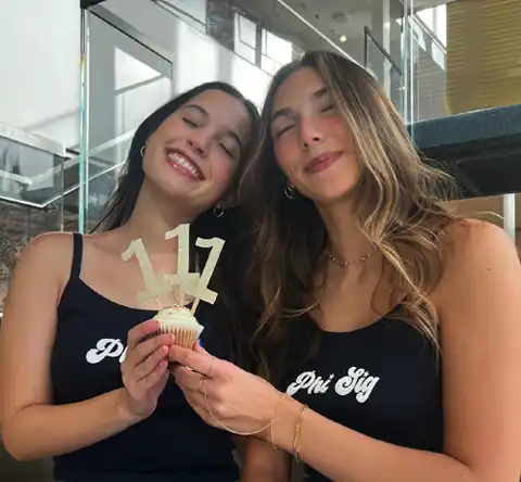 Female students smiling while holding a cupcake with 111th candles