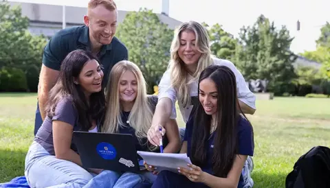 Smiling students looking at a laptop